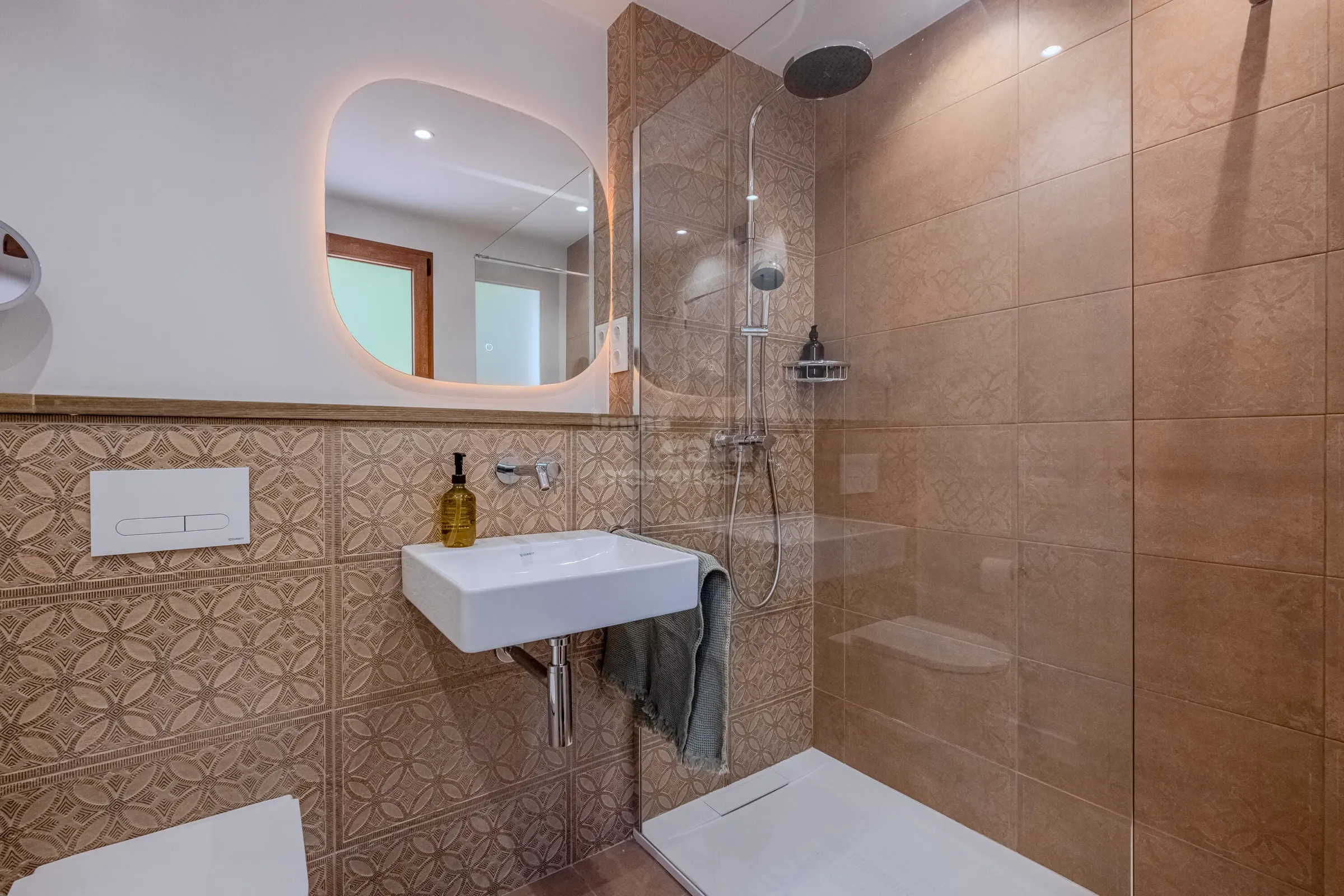 Walk-in rain shower clad in embossed terracotta tiles, with backlit mirror